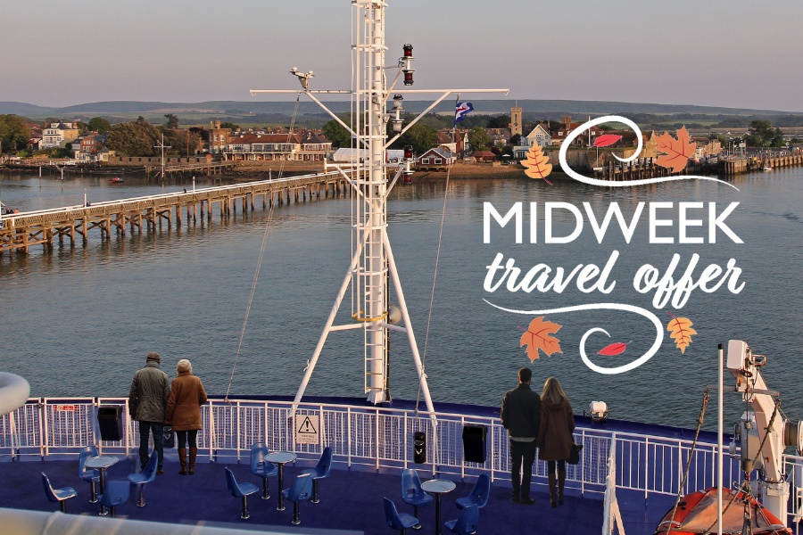 Two couples standing on the sun deck of a Wightlink ferry as it approaches Yarmouth harbour on a calm autumn evening, enjoying clear views of the pier and village.