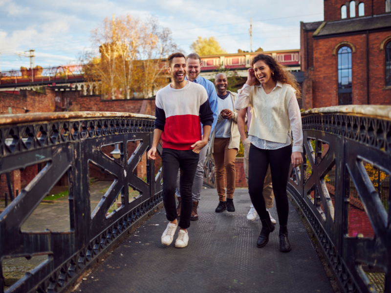 A group of friends walking on a bridge over water in Manchester - credit VisitBritain/Jacob Niblett