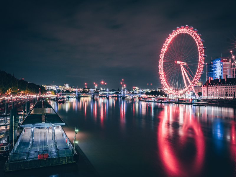 A river with a pontoon in the foreground, with the London Eye and other buildings lit up - credit VisitBritain/Andy Denial