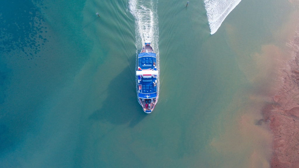 Aerial overhead view of a Wightlink ferry sailing through calm blue-green waters leaving a wake behind.