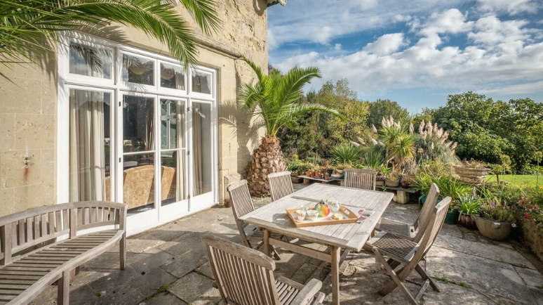 Outside patio of a historic building with stone work and well kept gardens