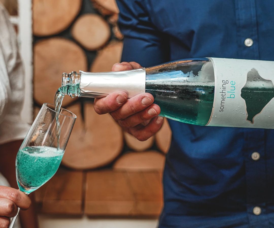 Blue sparkling wine being poured into a flute from a bottle of Something Blue at Adgestone Vineyard on the Isle of Wight.