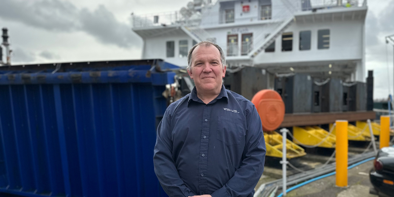 A man in a blue shirt stands in front of a ferry prow
