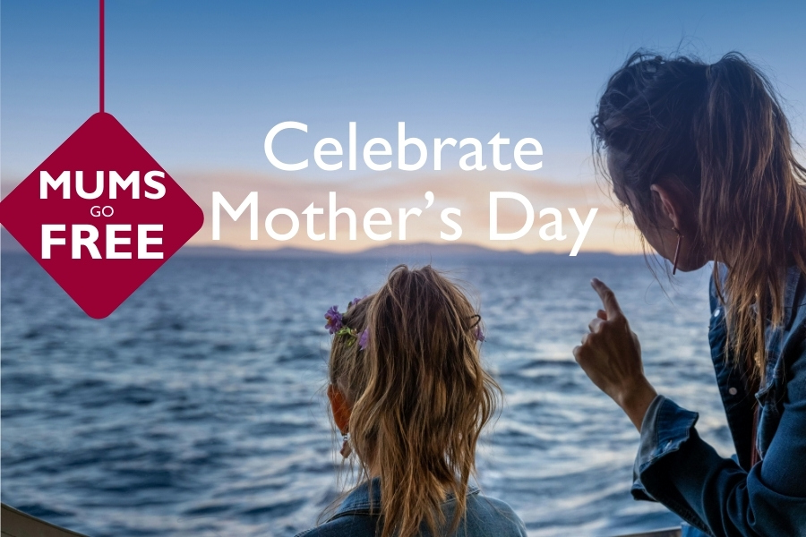 Mother and child standing on the deck of a ferry looking out across the sea at sunset, with text overlay reading “Celebrate Mother’s Day” and a red badge stating “Mums Go Free”.