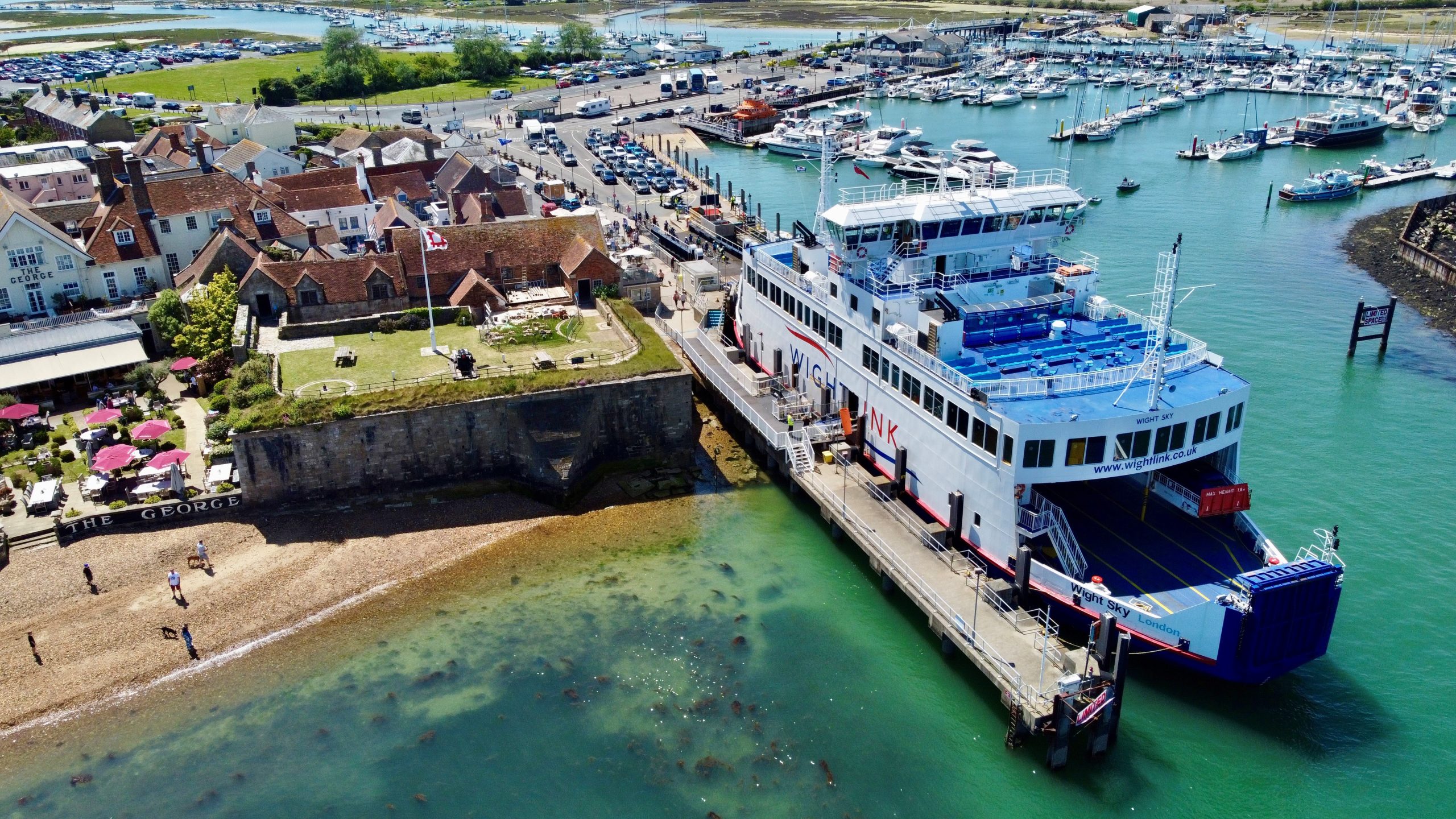 Wightlink ferry Wight Sky berthed at Yarmouth Harbour on the Isle of Wight, with the town’s waterfront, marina and boats visible on a sunny day.