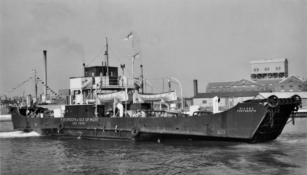Historic car ferry Hilsea docked in Portsmouth, with passengers and vehicles visible on deck and “Portsmouth & Isle of Wight Car Ferry” painted on the hull.