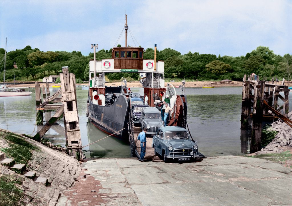 Colourised historic image of MV Wootton unloading 1950s cars down a slipway at Fishbourne, with crew guiding vehicles ashore.