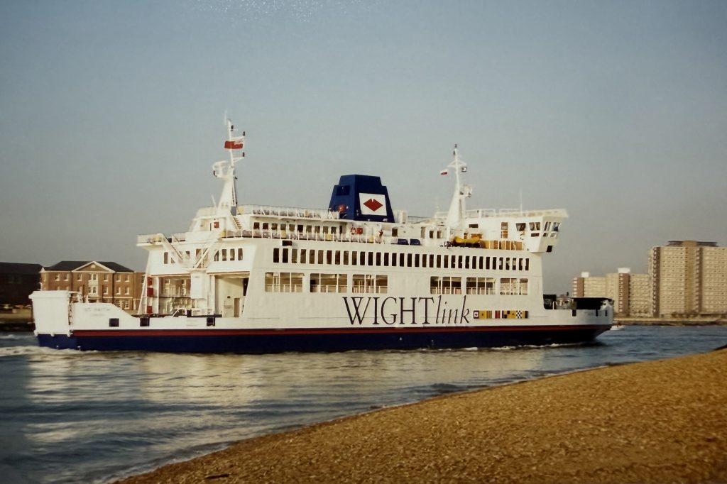 Wightlink ferry St Faith sailing past Portsmouth shoreline, showing early Wightlink branding on the white hull with city buildings in the background.
