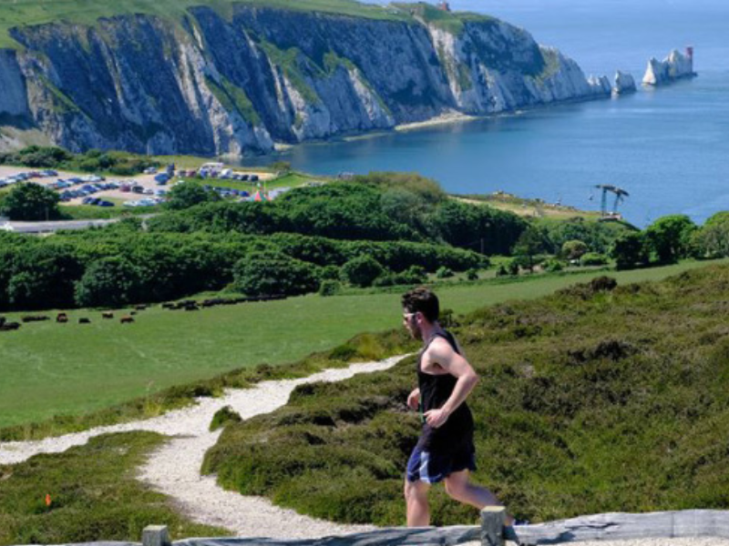 A man running on the Isle of Wight with The Needles in the background