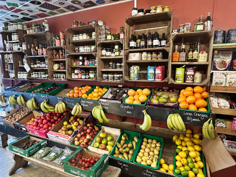 A well-stocked farm shop with fresh fruit and vegetables, plus shelves full of glass jars and bottles