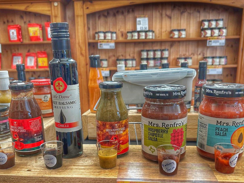 A selection of bottles and jars with chilli-based products inside a farm shop