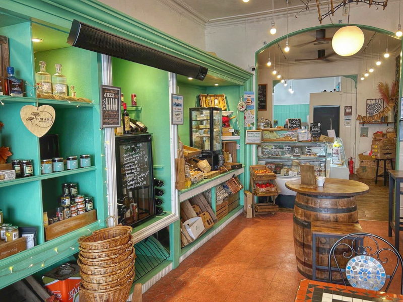 Inside a small farm shop with colourful shelves, baskets and barrels on display