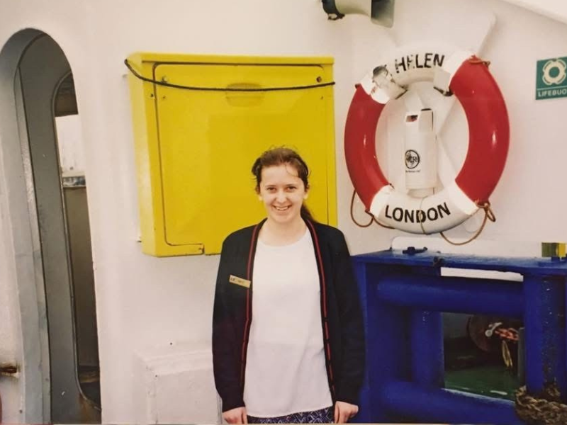 A woman in a Wightlink uniform poses onboard a ship next to a St Helen lifering