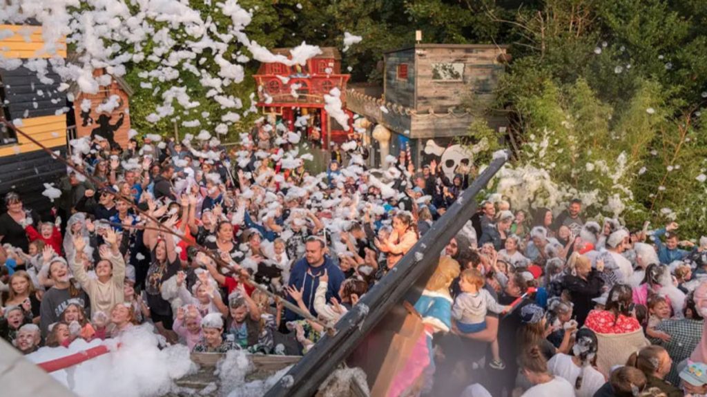 Families and children enjoy a foam party at Blackgang Chine, with bubbles filling the air and pirate-themed attractions creating a lively atmosphere.