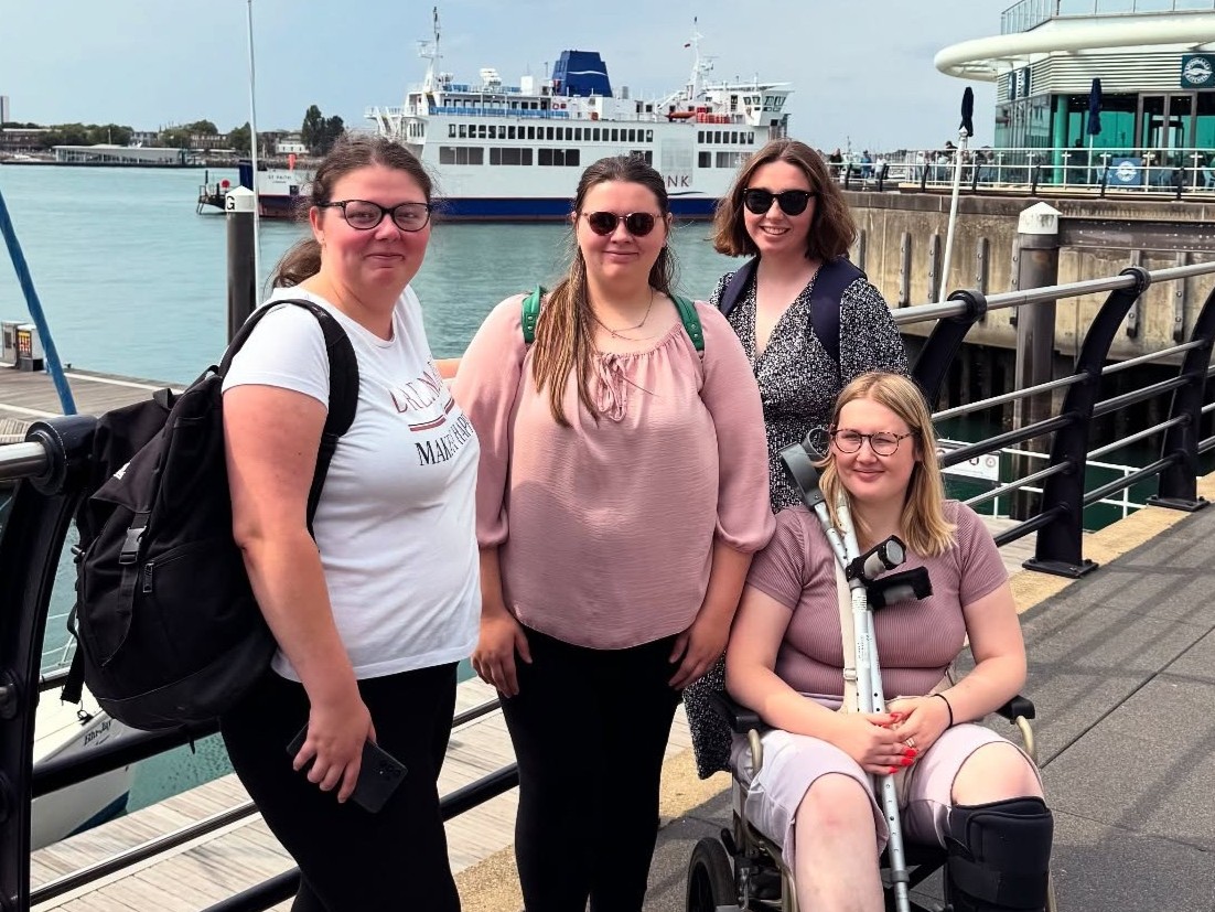 Group of young people by Portsmouth harbour with a Wightlink ferry in the background, highlighting participation in a youth travel initiative.