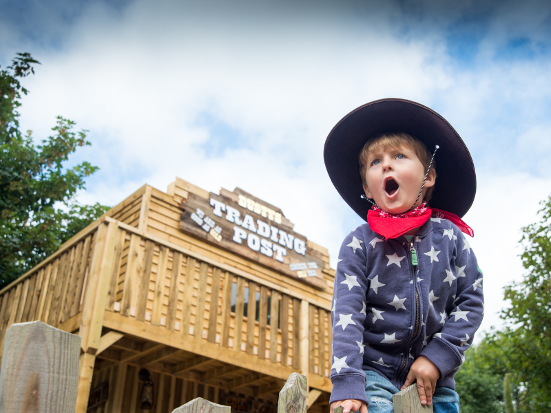 A boy dressed up in a cowboy hat and neckerchief outside a wild-west-style building at Blackgang Chine, Isle of Wight