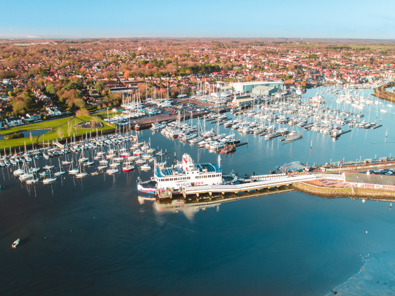 An aerial view of Lymington harbour showing yachts in the marina, the town and a Wightlink ferry in port