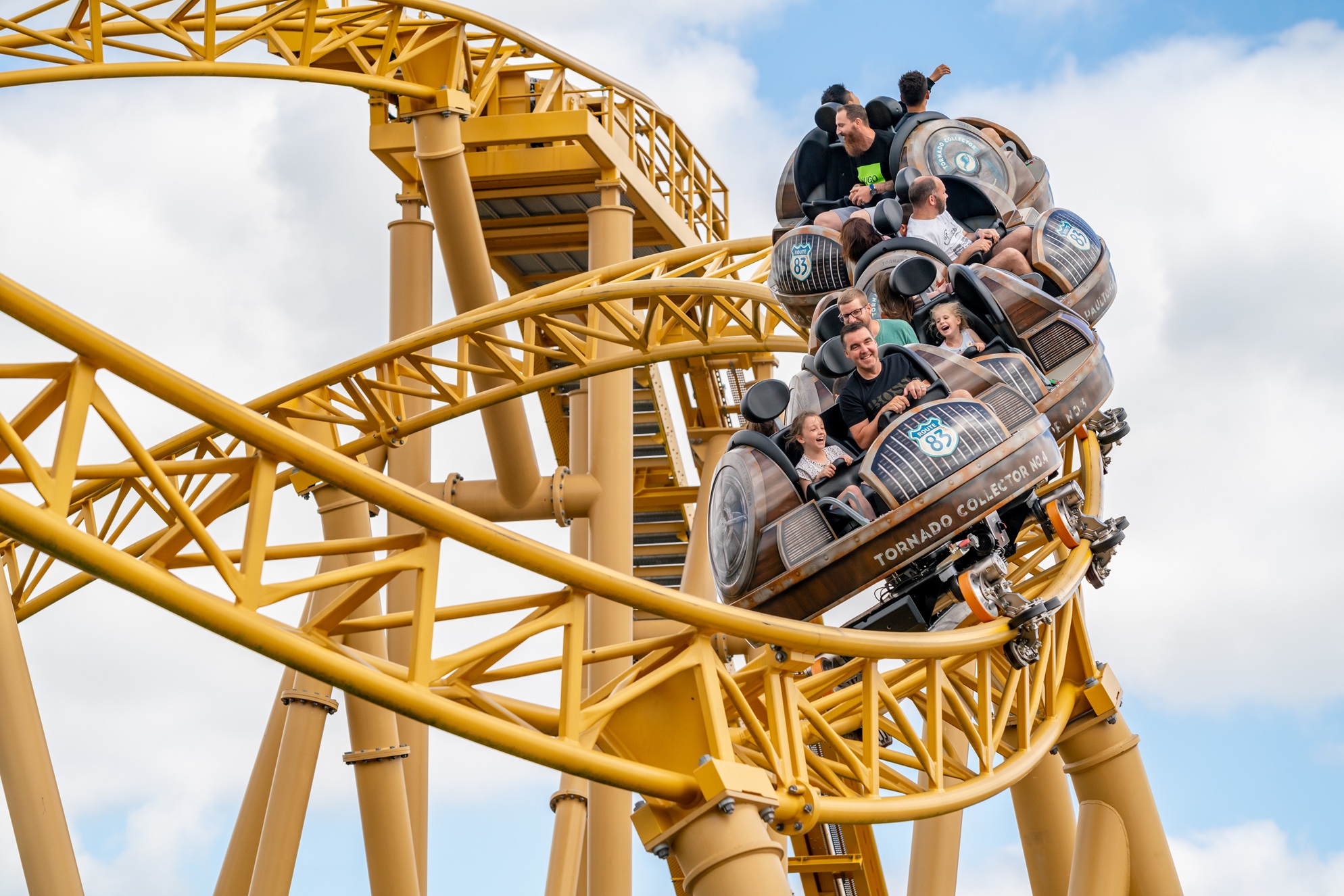 Guests ride a themed rollercoaster as the train twists through bright yellow track at Paultons Park.