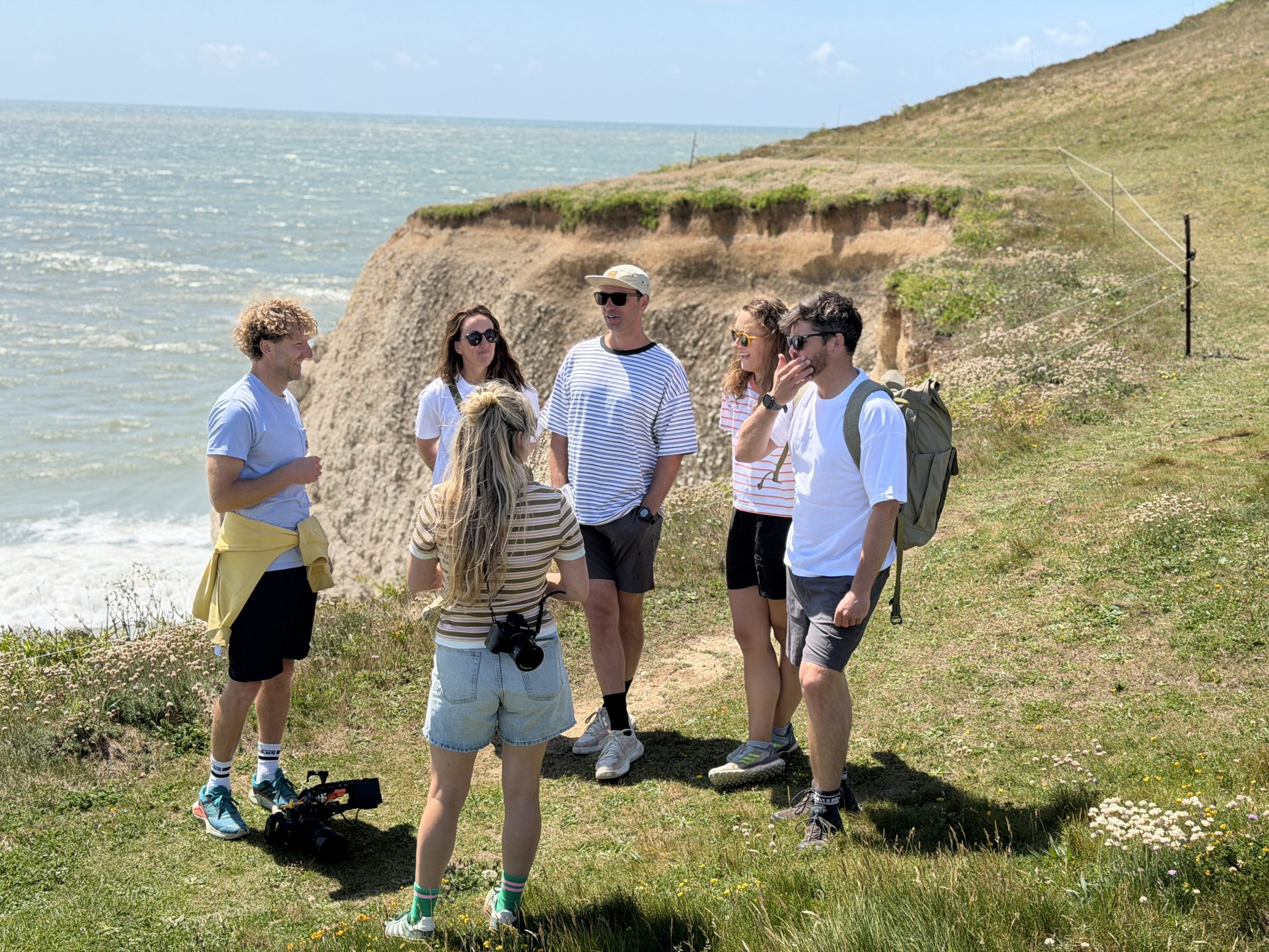 A group of visitors stand on the clifftop at Tennyson Down, enjoying panoramic coastal views during filming for Wightlink's 48 Hours on Island Time campaign.