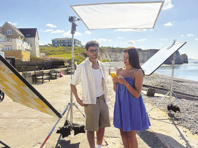 A couple being filmed on Freshwater beach, Isle of Wight. They are surrounded by lighting equipment.
