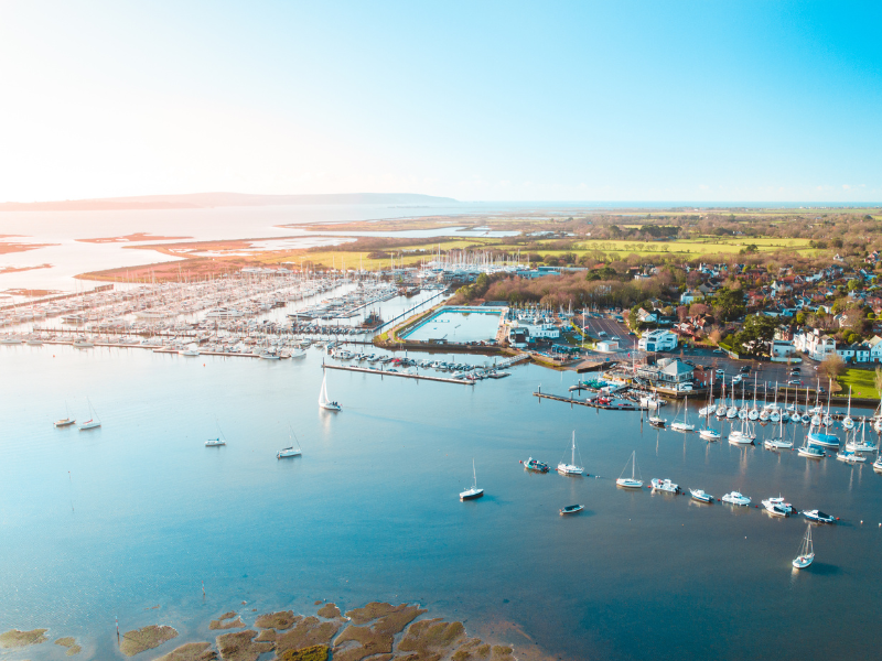An aerial shot of Lymington river and the New Forest coastline beyond. You can see yachts and marinas as well as green land.