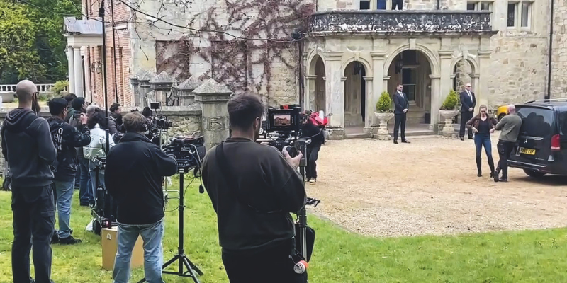 A film crew filming a scene in front of a historic house on the Isle of Wight