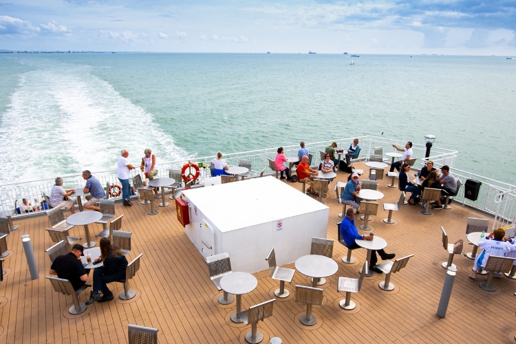Passengers enjoying the outdoor sun deck on a Wightlink ferry crossing to the Isle of Wight.