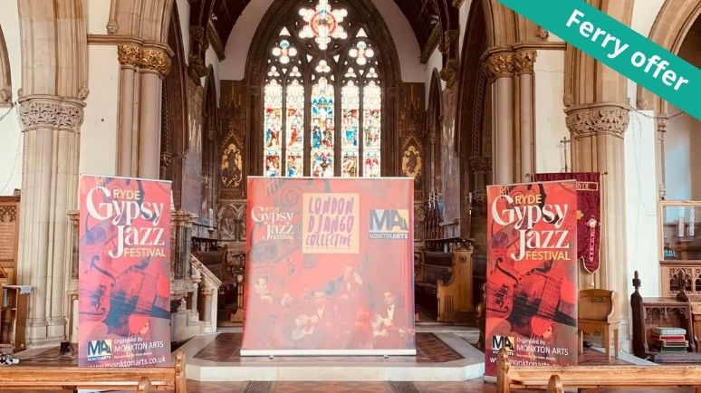 Stage setup for the Ryde Gypsy Jazz Festival inside a historic church, featuring festival banners and a central performance backdrop beneath stained-glass windows and ornate stone arches.