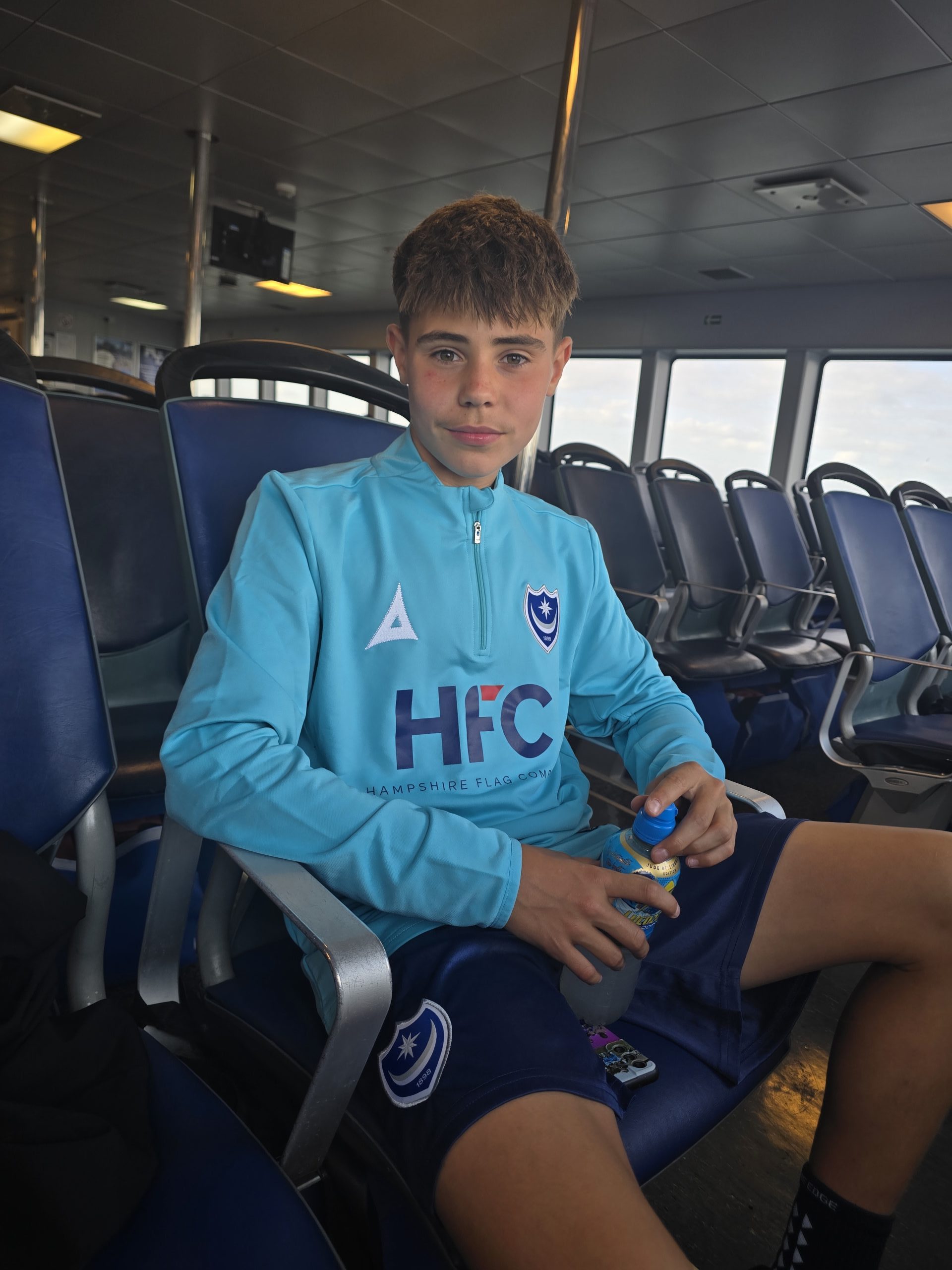 Young Portsmouth FC community programme player travelling on a Wightlink ferry to football training on the mainland.