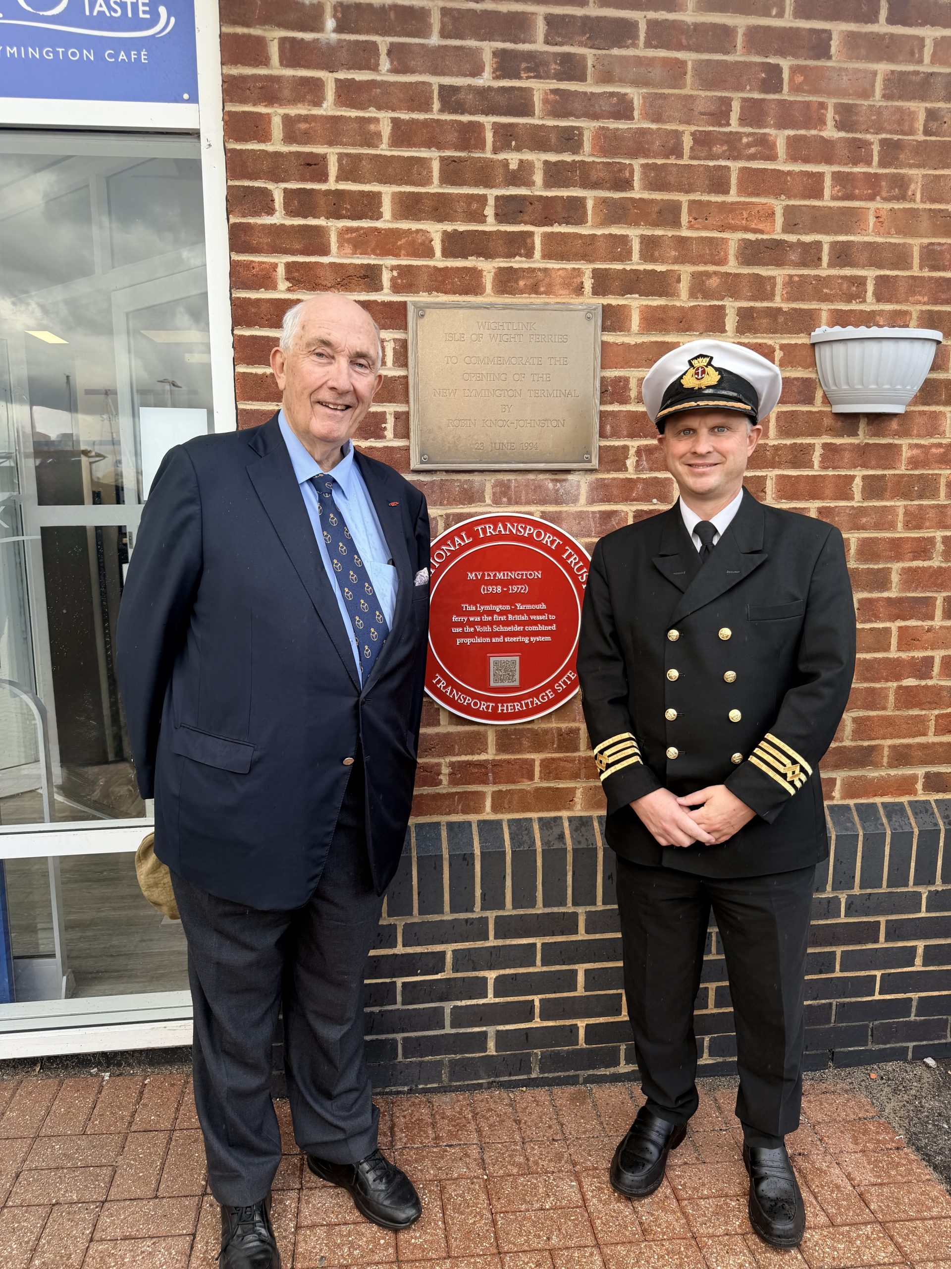 National Transport Trust representative and Wightlink Head of Fleet Operations standing beside the Red Wheel plaque commemorating MV Lymington at Wightlink's Lymington ferry terminal.